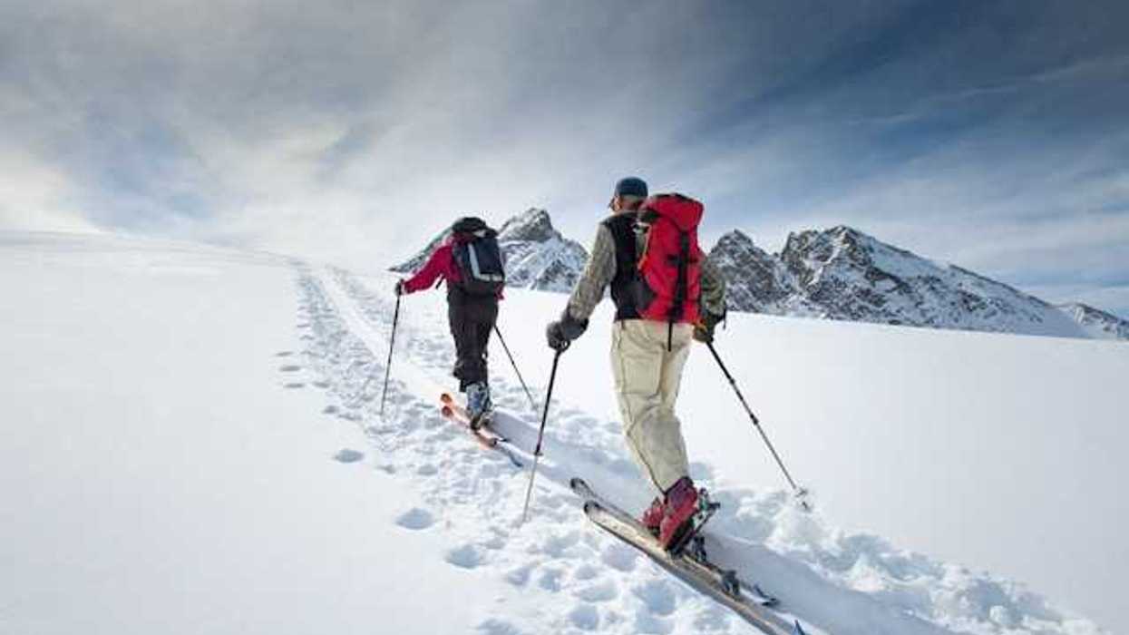 Two skiiers moving up a snowy mountain