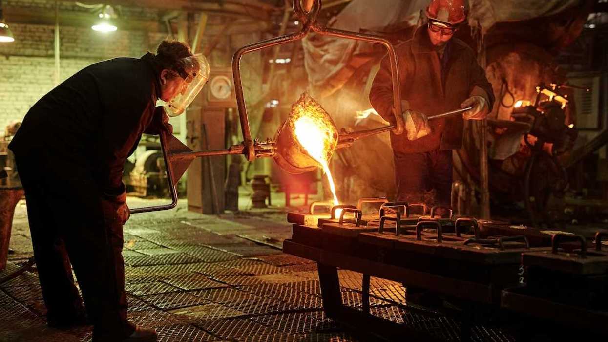 Two steel/iron foundry workers pouring molten material