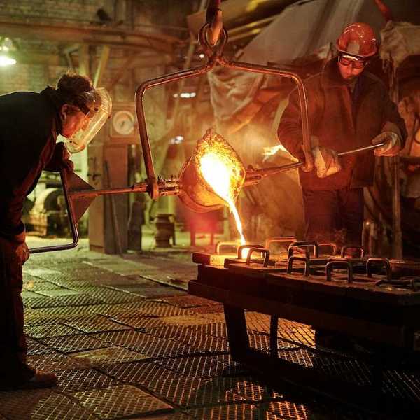 Two steel/iron foundry workers pouring molten material