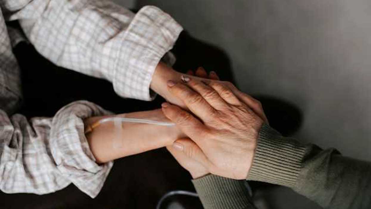 Two women holding hands, one with an IV attached