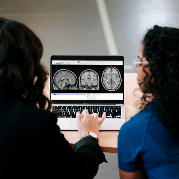 Two women looking at a computer screen with mri brain images on it