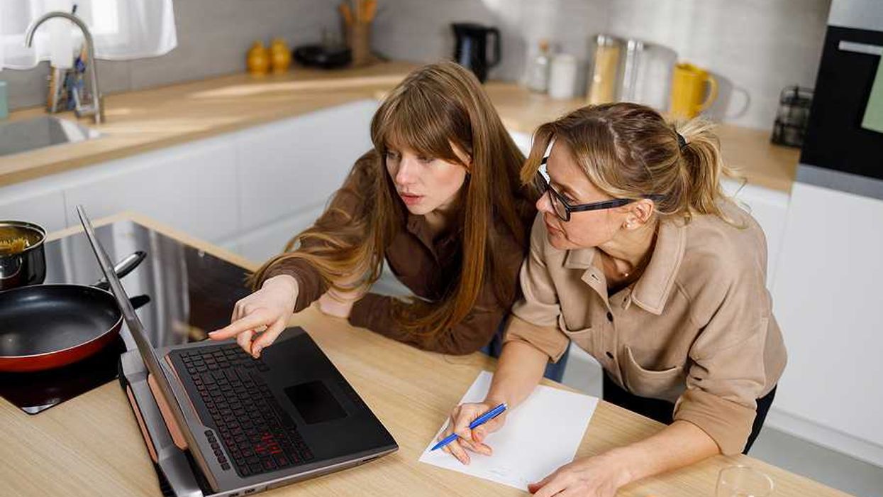 Two women looking at a laptop on the kitchen counter