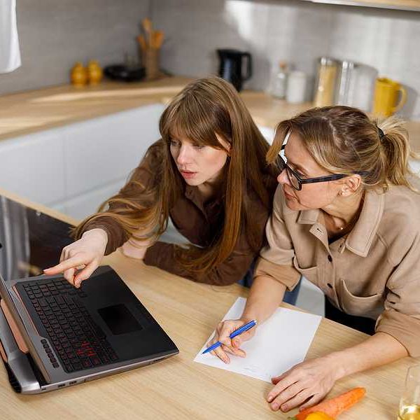 Two women looking at a laptop on the kitchen counter