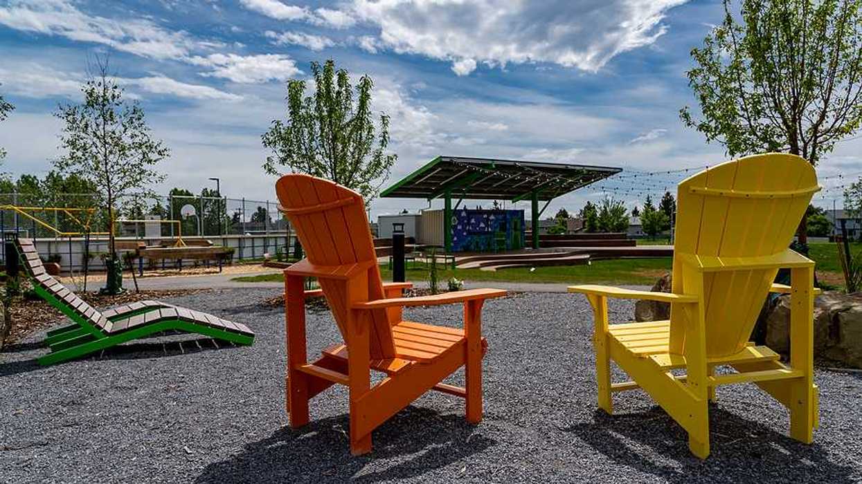 Two wooden chairs next to a field that has a solar shade panel over it