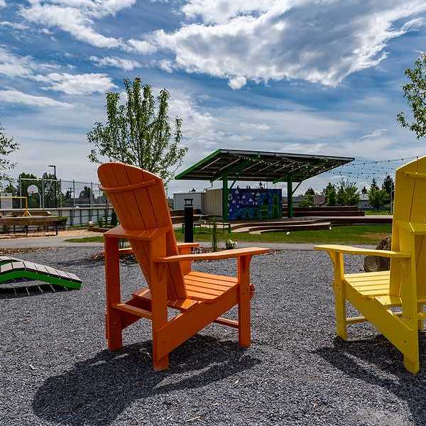 Two wooden chairs next to a field that has a solar shade panel over it