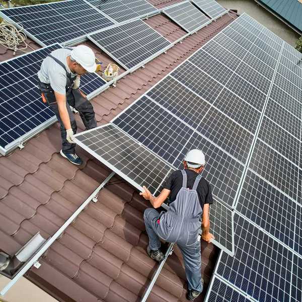 Two workers installing rooftop solar on a curved-tile roof
