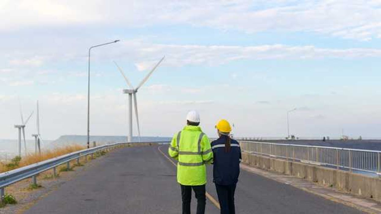 Two workers looking at wind turbines