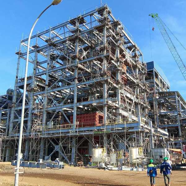 Two workers walk towards an industrial site under construction