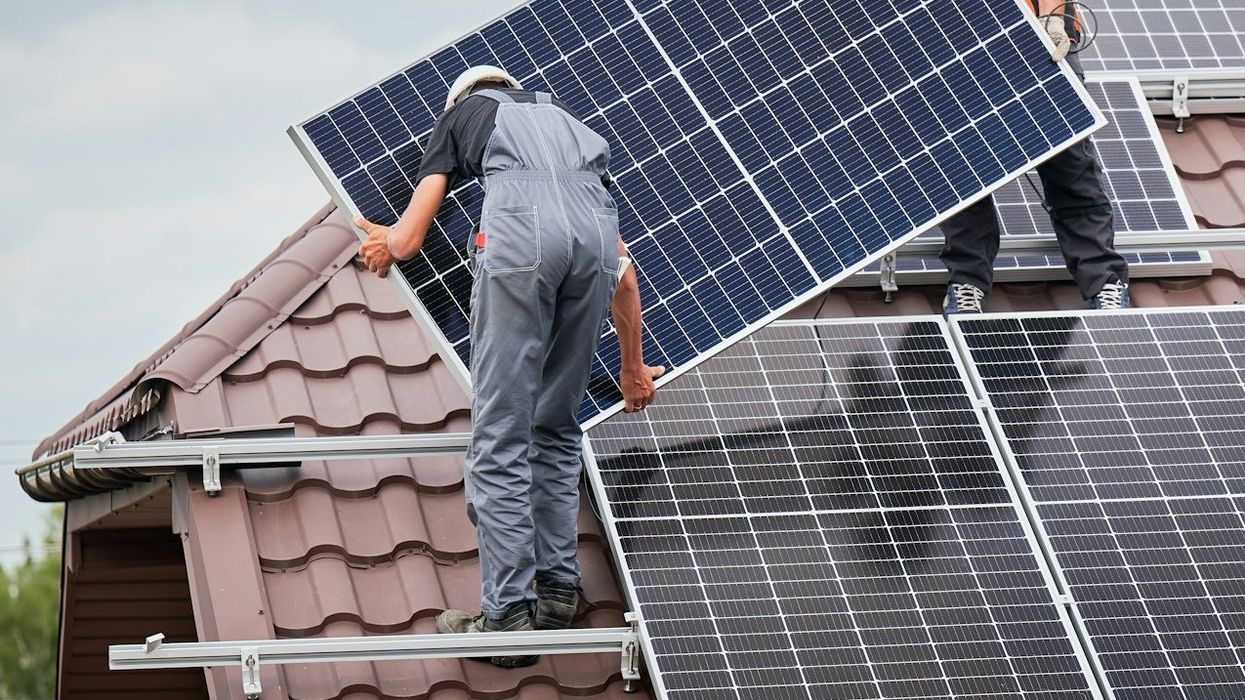 Two workmen installing rooftop solar panels