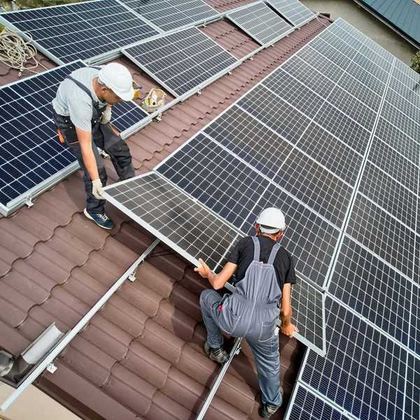 Two workmen installing solar panels on a rooftop