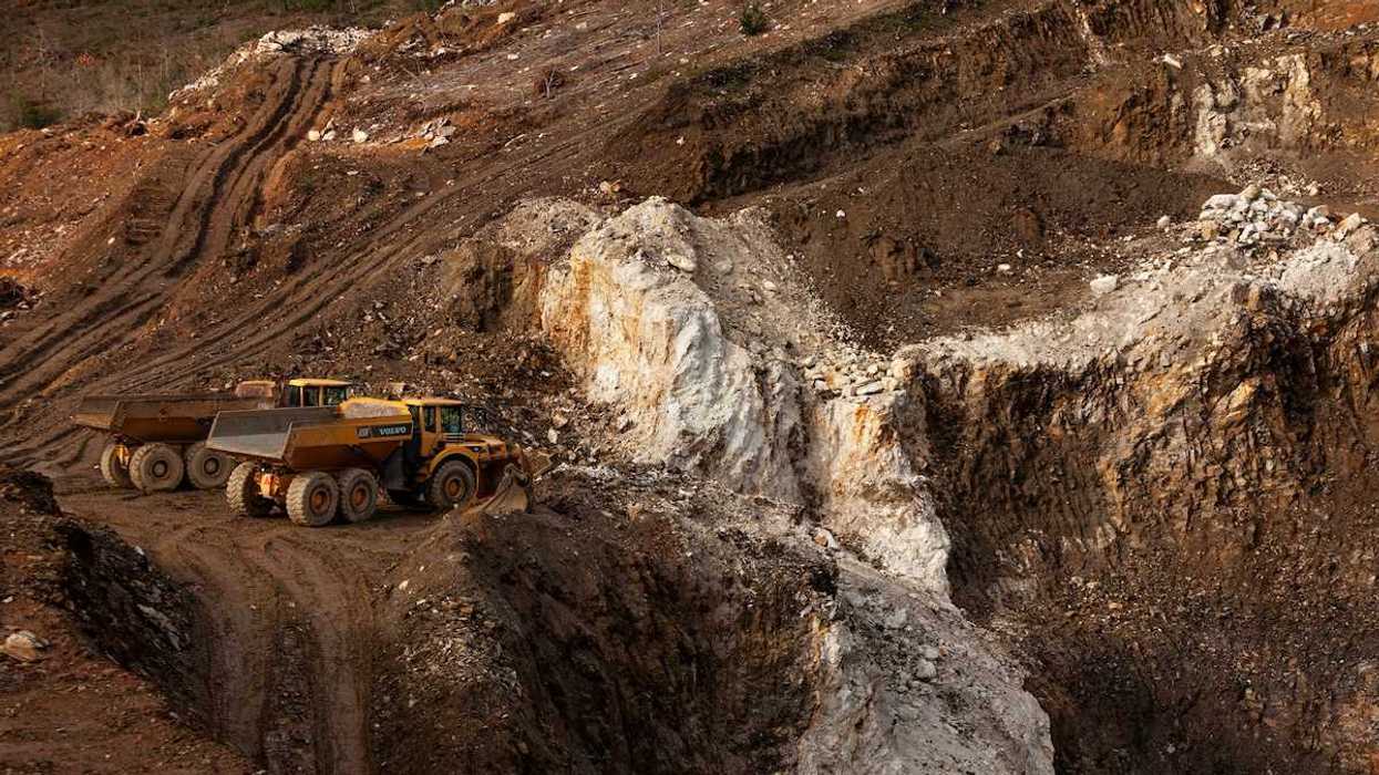 Two yellow rock trucks parked in a lithium mining cut