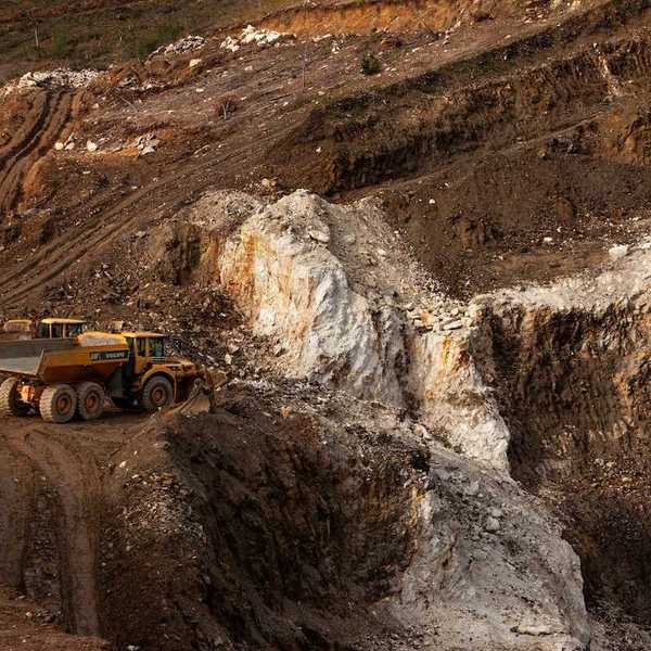 Two yellow rock trucks parked in a lithium mining cut
