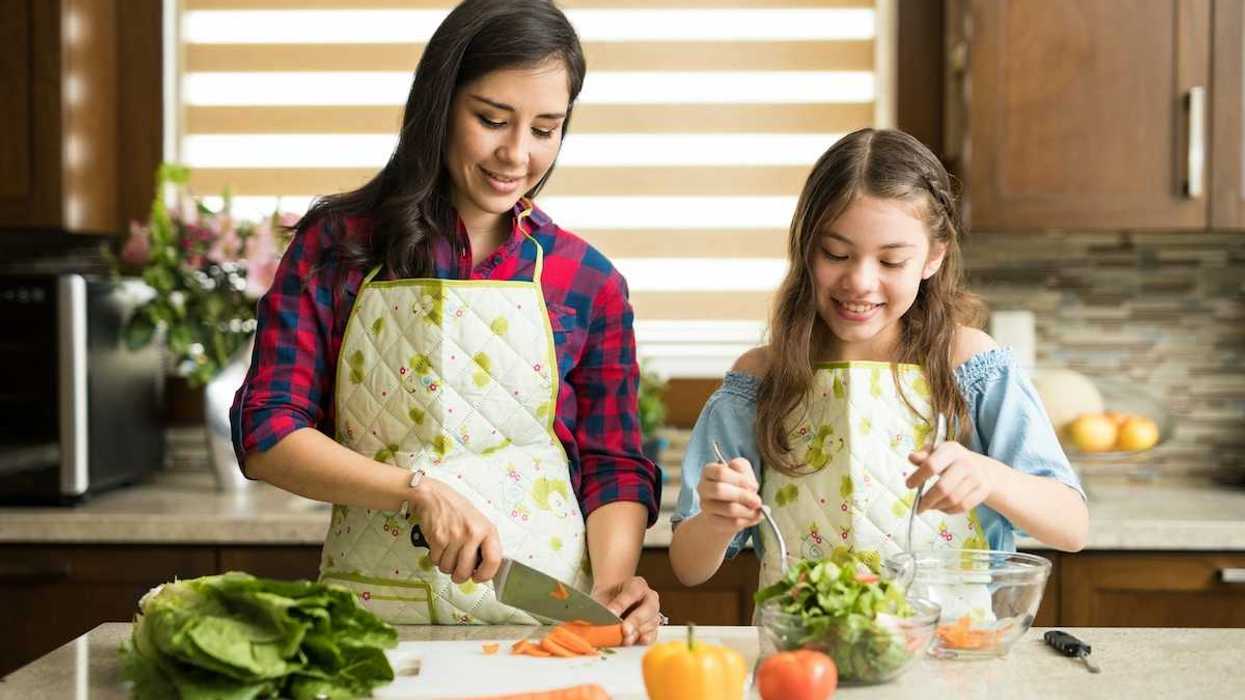 Two young women preparing fresh, healthy, food - slicing carrots and tossing salad.