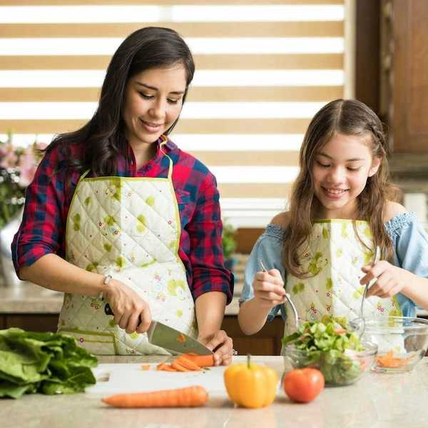 Two young women preparing fresh, healthy, food - slicing carrots and tossing salad.