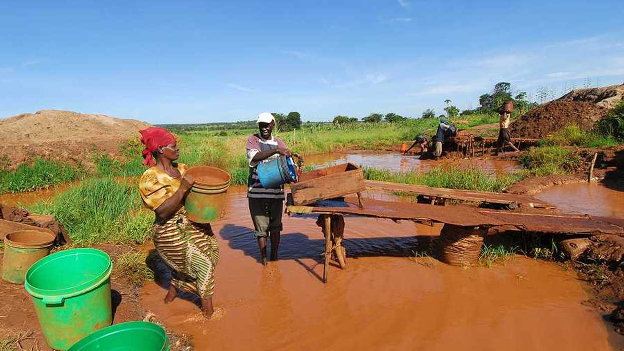 Two Zimbabweans pouring water into a mining ramp