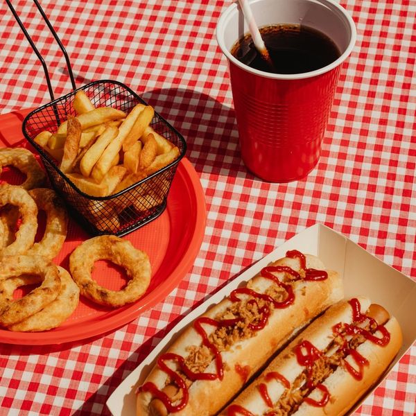 Ultra-processed fast food: onion rings. french fries, hot dogs, cola in plastic cup.