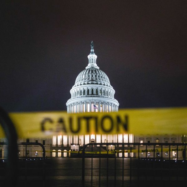 US capitol building illuminated at night with yellow caution tape across the foreground.