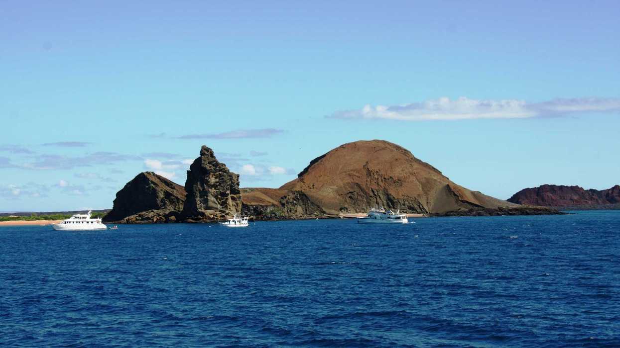 View of Galápagos island and white boats from a distance.