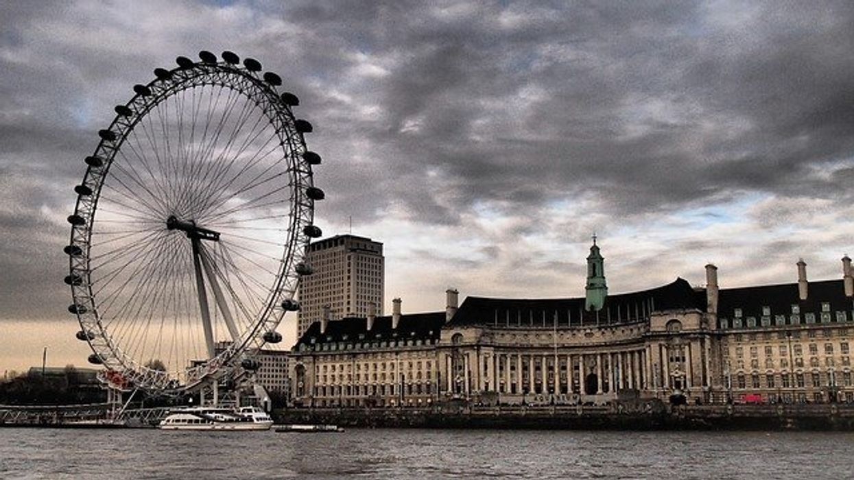 View of London ferris wheel under cloudy sky.