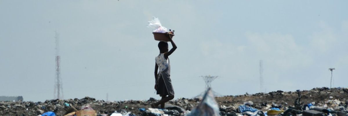 waste picker in landfill with a basket on their head.