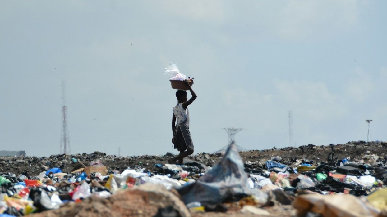 waste picker in landfill with a basket on their head.