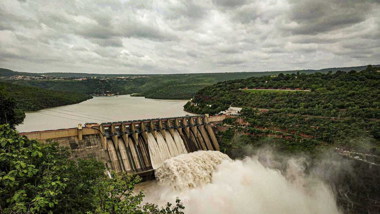 Water flowing from dam under cloudy sky during daytime.