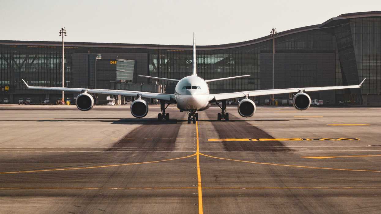 White airplane viewed from the front on the tarmac with an airport terminal in the background