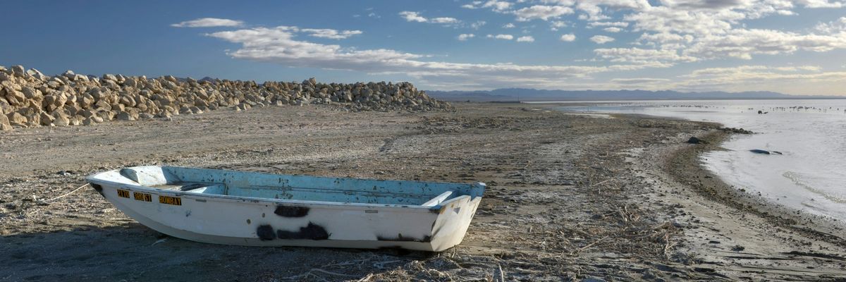white and blue boat on brown sand under blue sky during daytime.