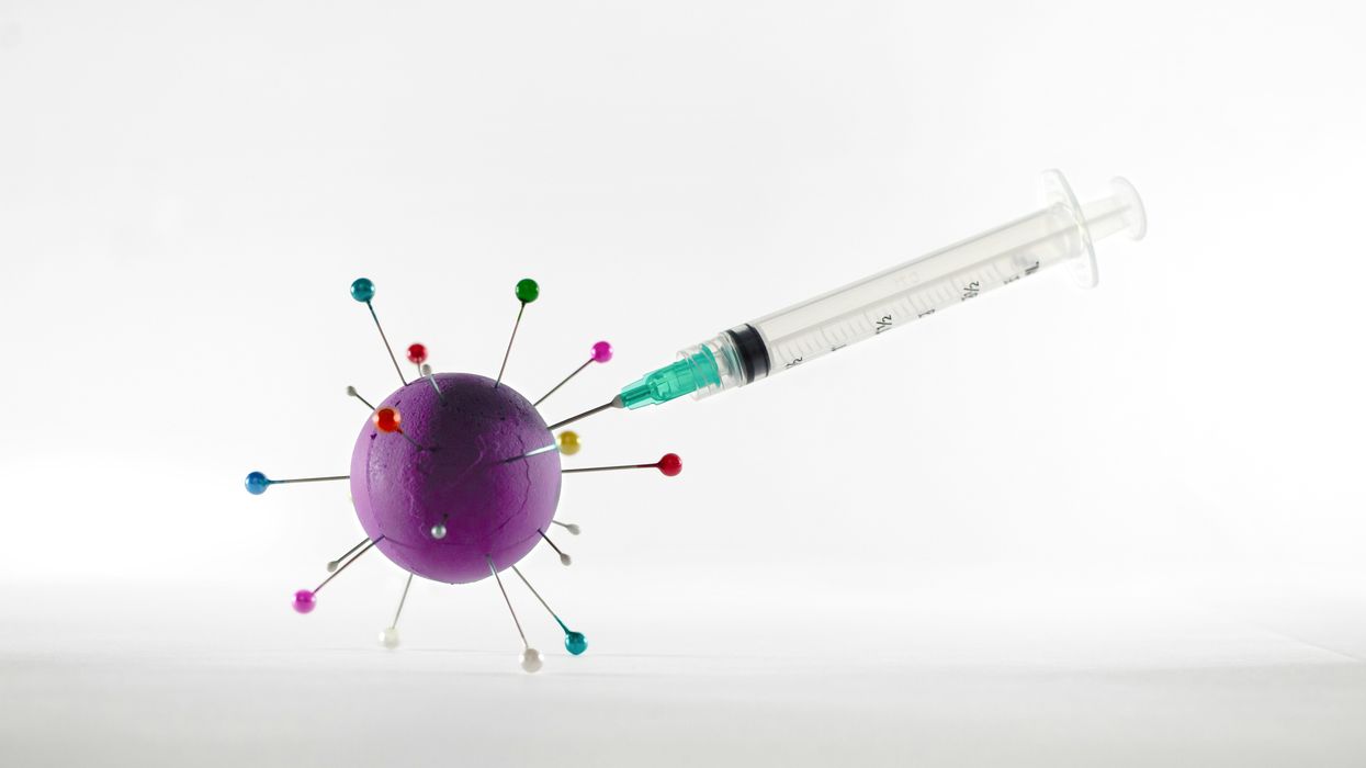 white and green syringe on white surface stuck into a purple ball.