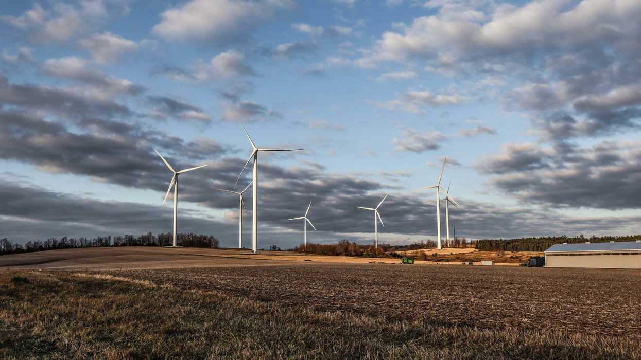 white wind turbines on brown grass field under white clouds and blue sky during daytime.
