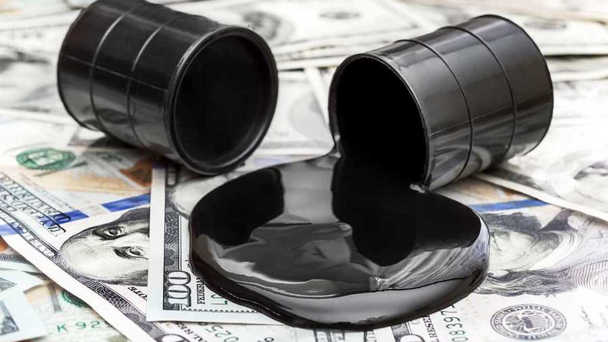 Whole barrel of oil and crude oil spilled from barrel on the dollar bills.