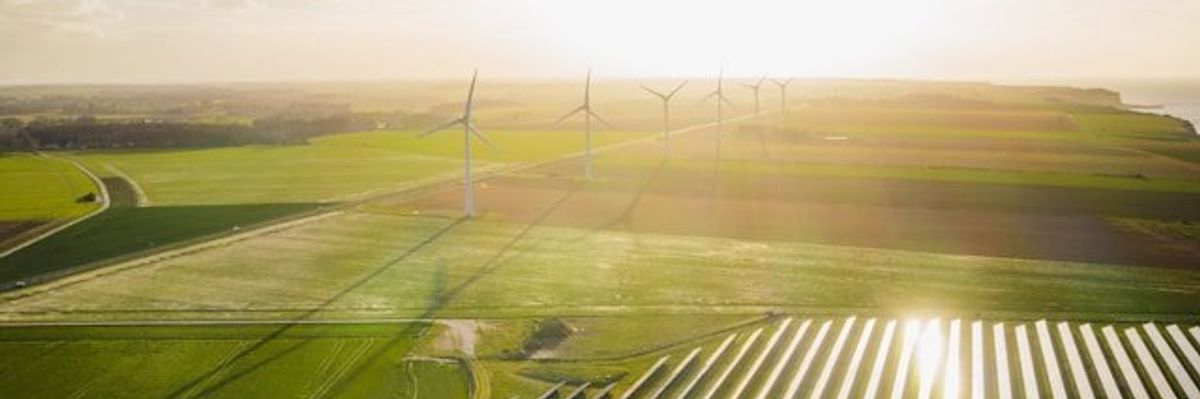 Wind turbines and solar energy panels set in farmland.