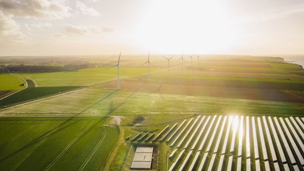 Wind turbines and solar energy panels set in farmland.