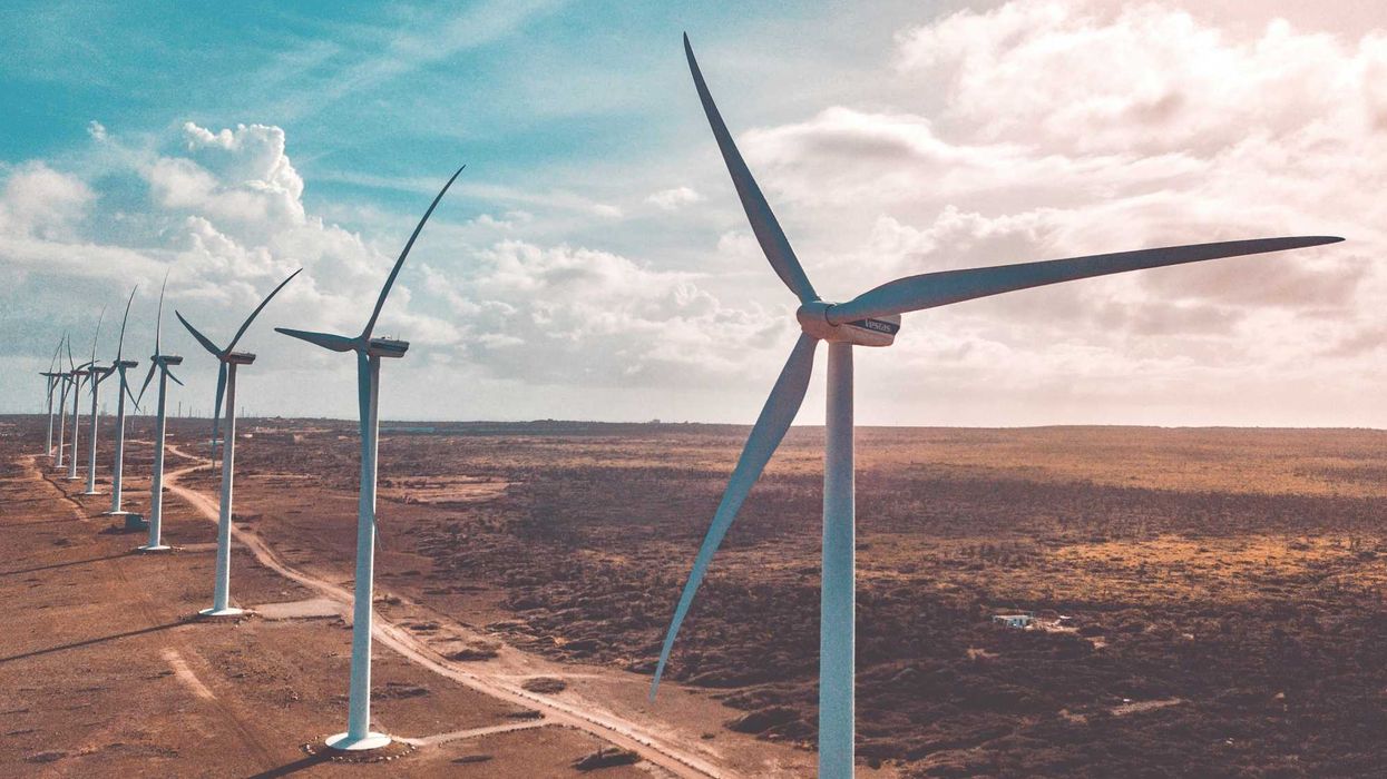 wind turbines on brown sand under white clouds and blue sky during daytime