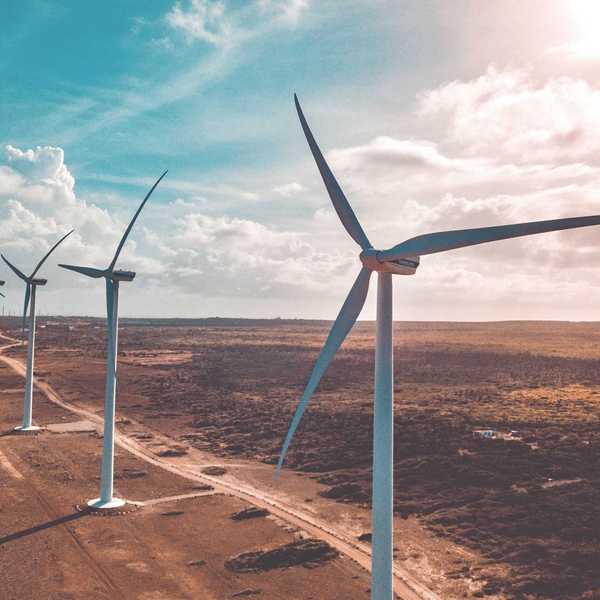 wind turbines on brown sand under white clouds and blue sky during daytime