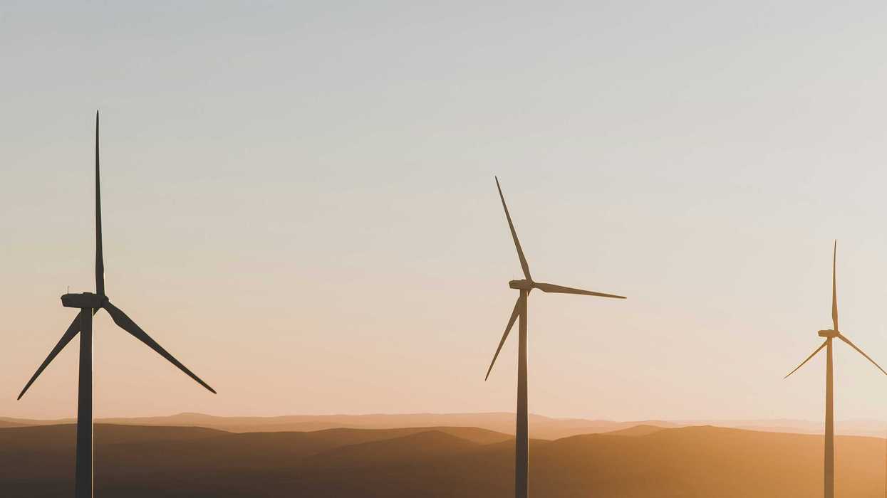Wind turbines silhouetted on a ridge in late afternoon sun.