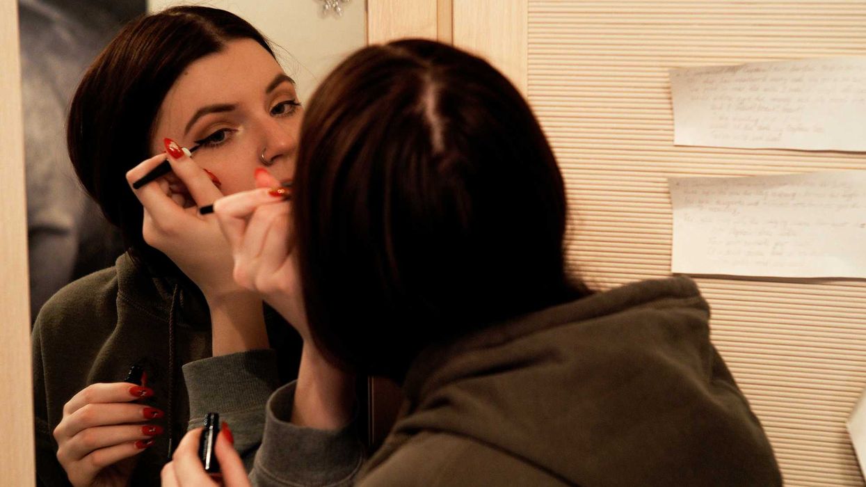 woman applying eyeliner in the mirror.