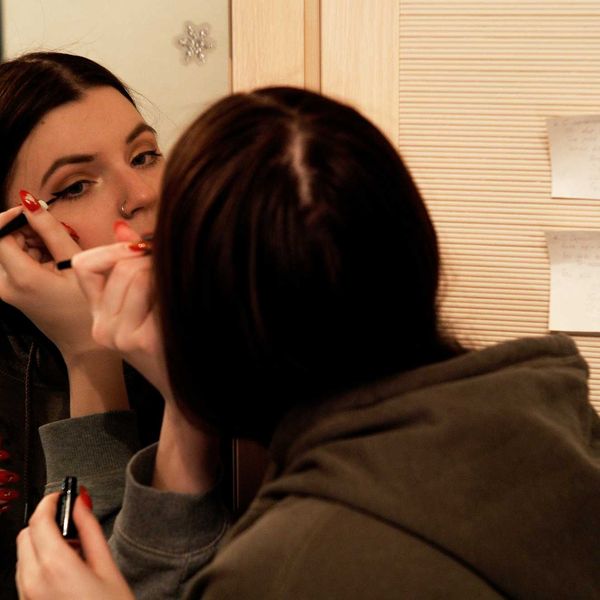 woman applying eyeliner in the mirror.
