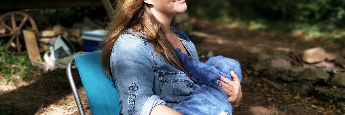 woman breastfeeding baby while sitting on chair