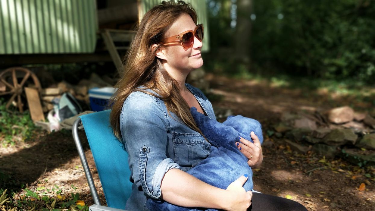 woman breastfeeding baby while sitting on chair