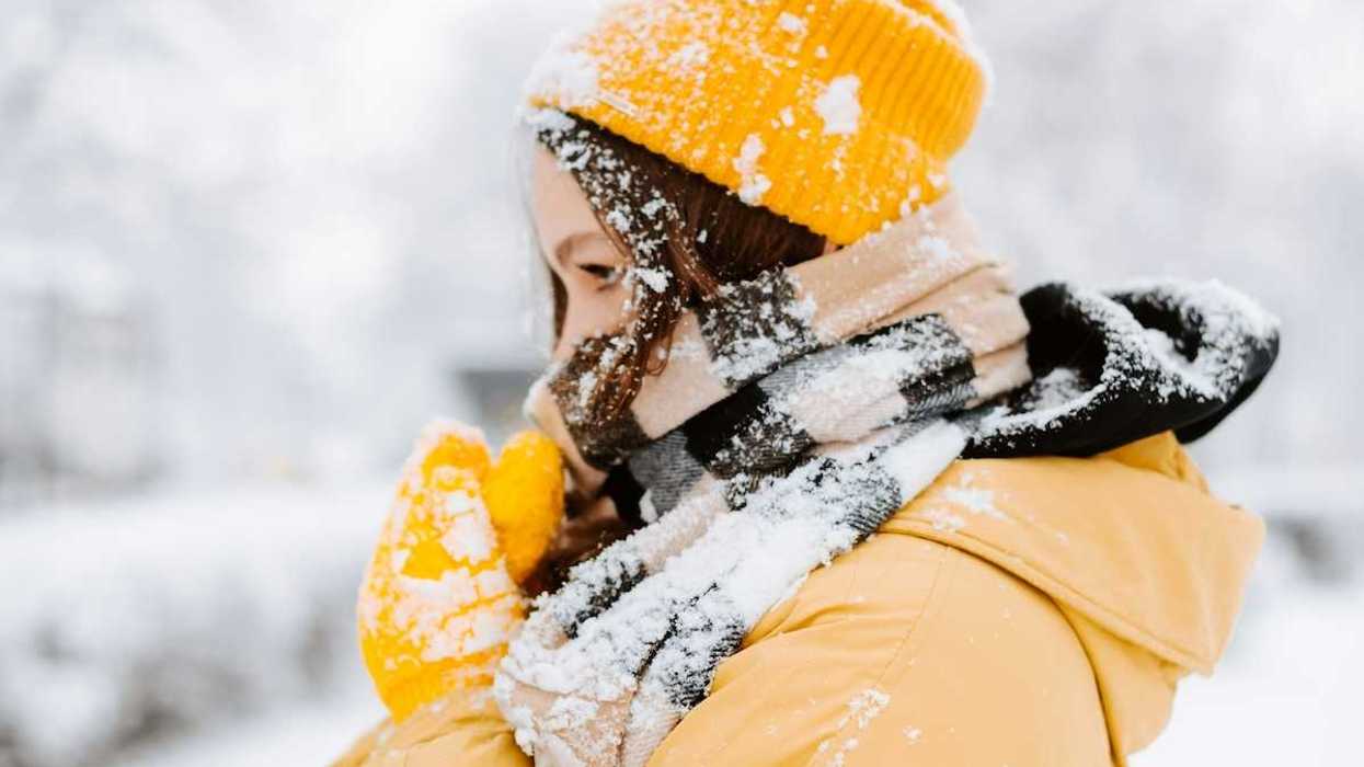 Woman bundled against cold, snowy weather wearing yellow coat andyellow hat.