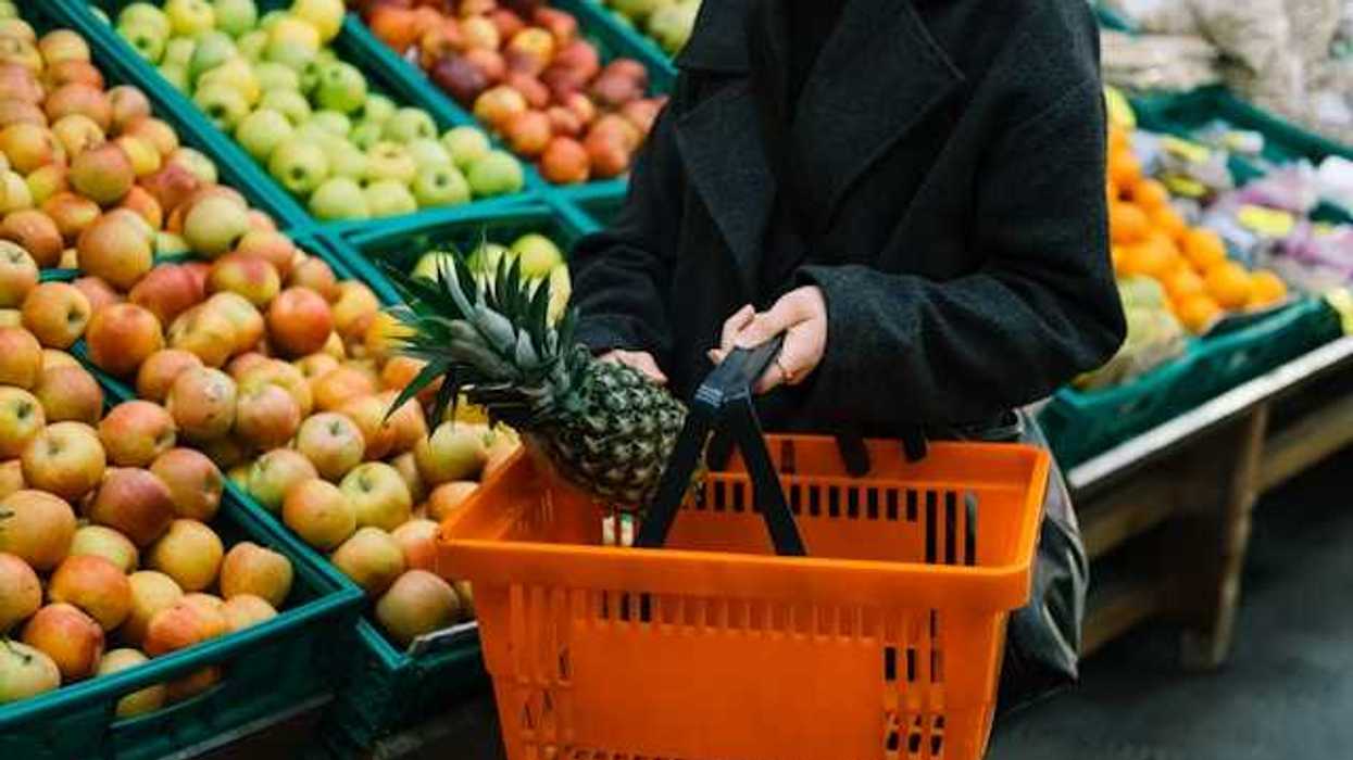 Woman carrying a hand cart in the vegetable and fruit section of a grocery store