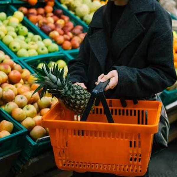 Woman carrying a hand cart in the vegetable and fruit section of a grocery store