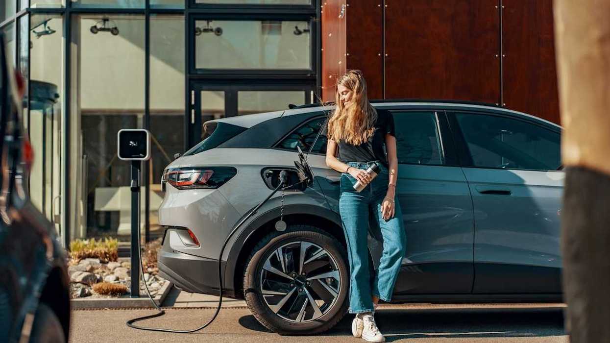 Woman dressed in blue jeans and black top casually charging an EV