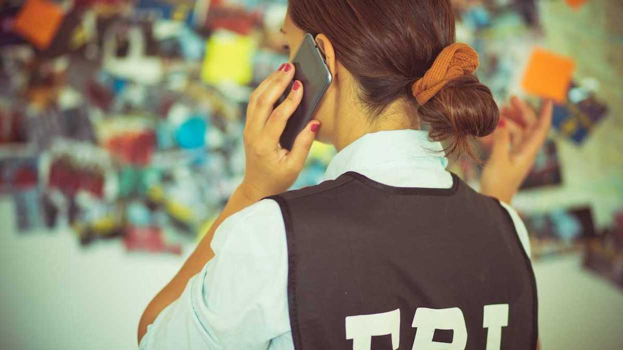 Woman FBI agent, back to camera, talking on the phone.