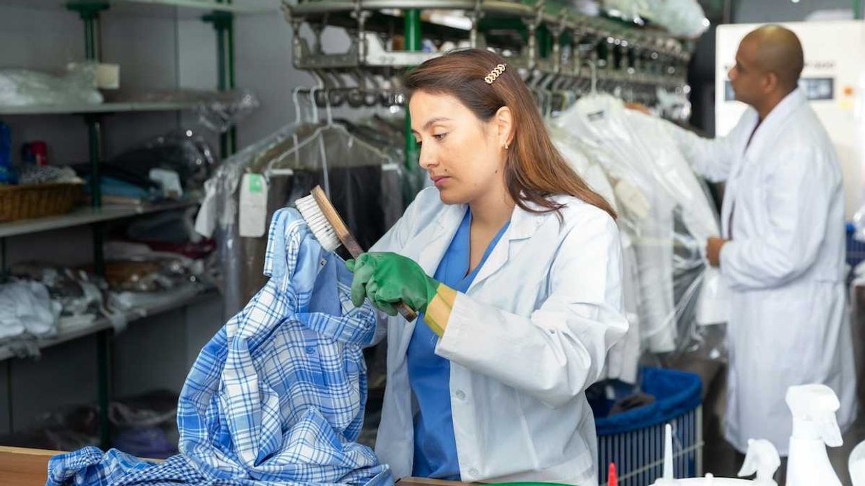 Woman hand treating garments at dry cleaning establishment