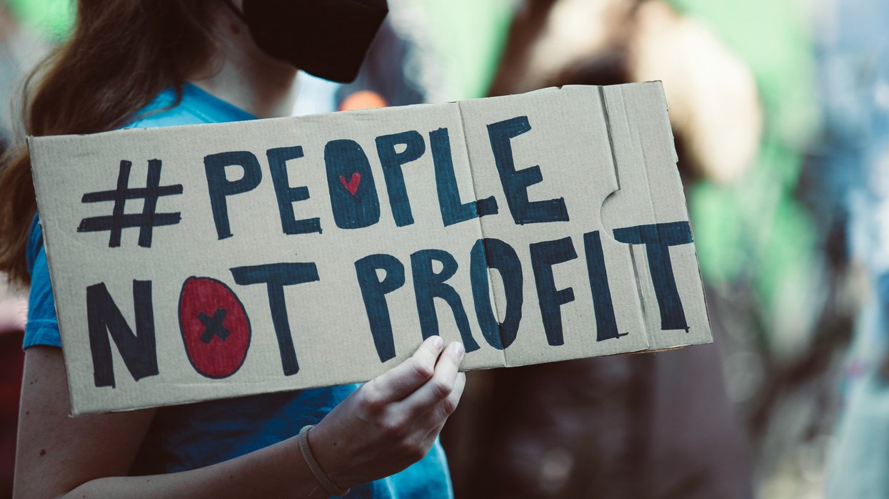 woman holding sign that says # People Not Profit