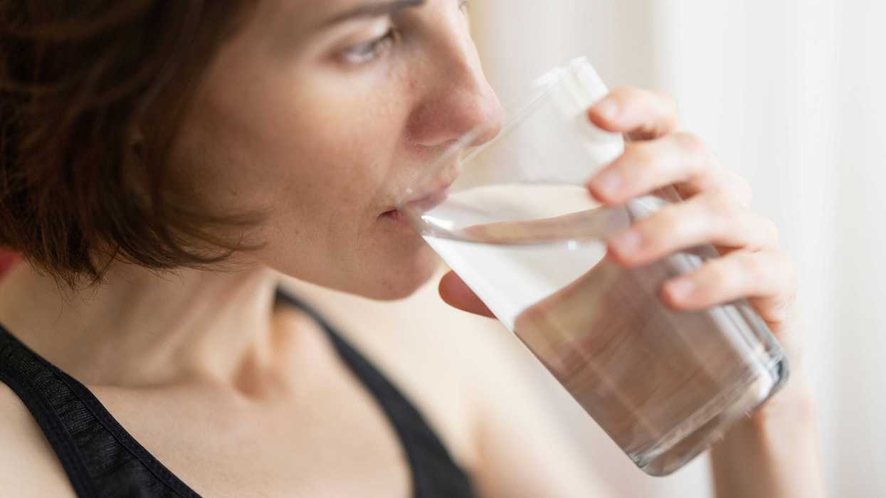 woman in black tank top drinking water.