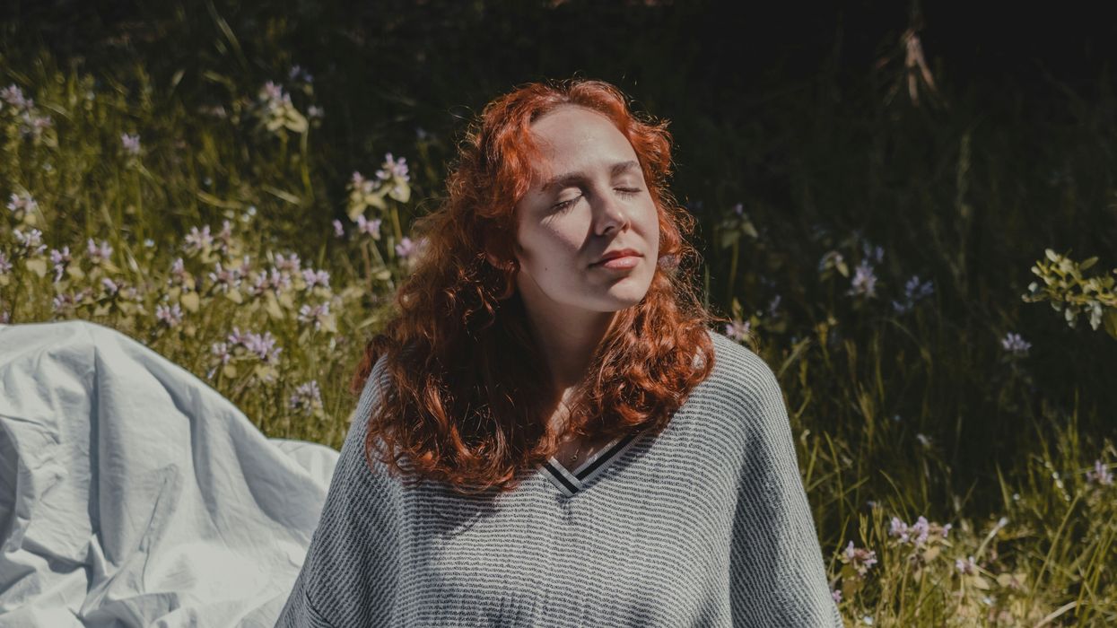woman in gray sweater sitting on white textile in sun