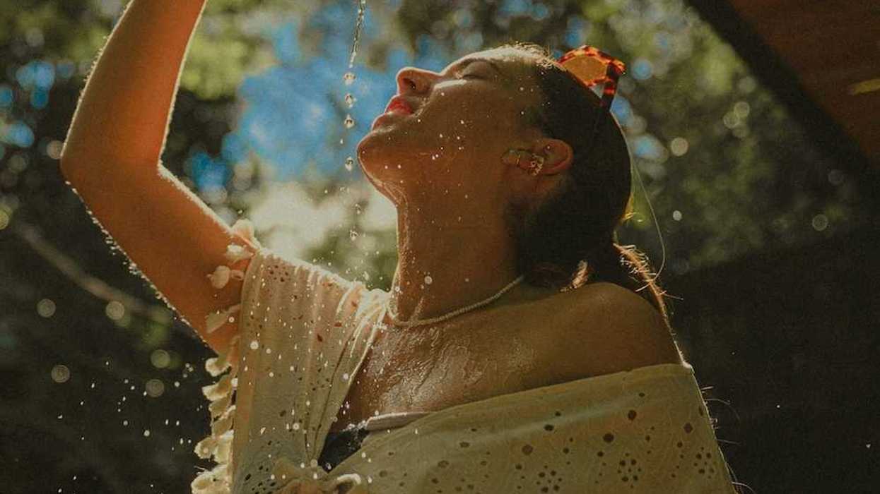 Woman in light clothing, cooling off by pouring water over herself.